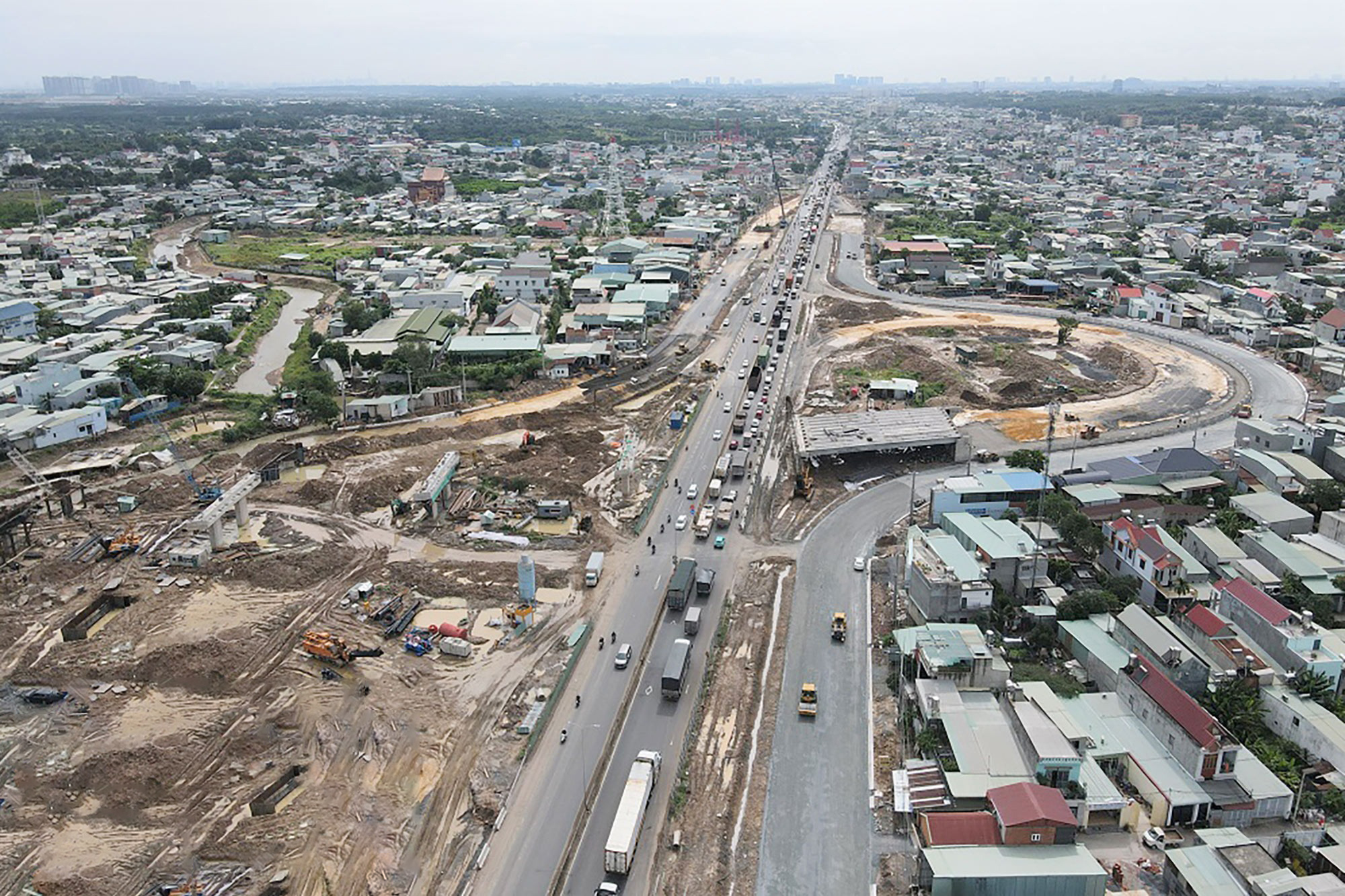 Toàn cảnh trục đường Võ Nguyên Giáp đoạn qua huyện Long Thành Đồng Nai năm 2026, hai bên đường là các lô đất nền phân lô cắm cọc nhựa tạm thời, phía xa là công trường sân bay Long Thành