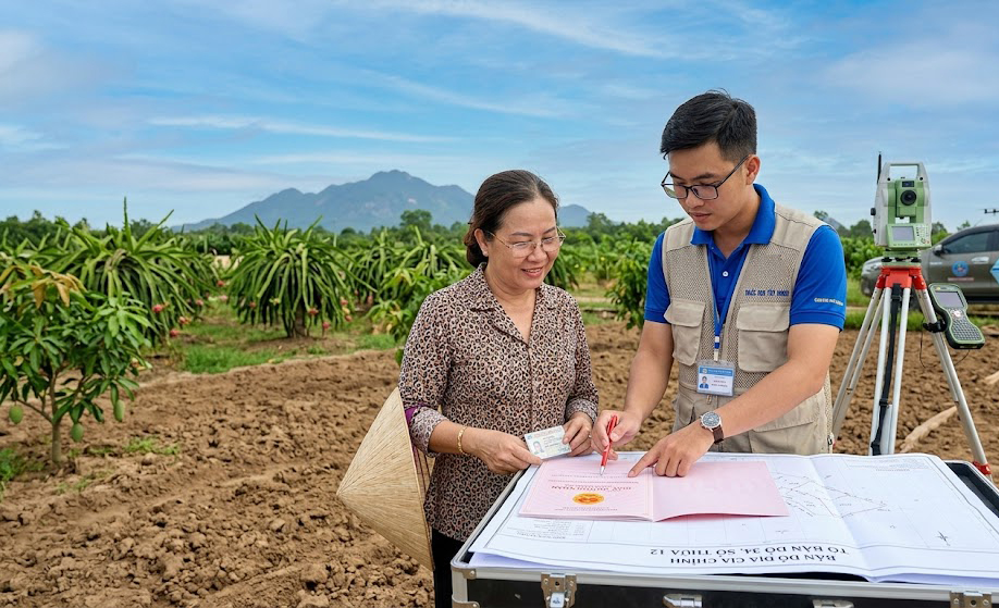 Chủ đất và kỹ sư trắc địa đang đối chiếu sổ đỏ và bản đồ địa chính tại thực địa một thửa đất vườn tại huyện Châu Thành, Tây Ninh